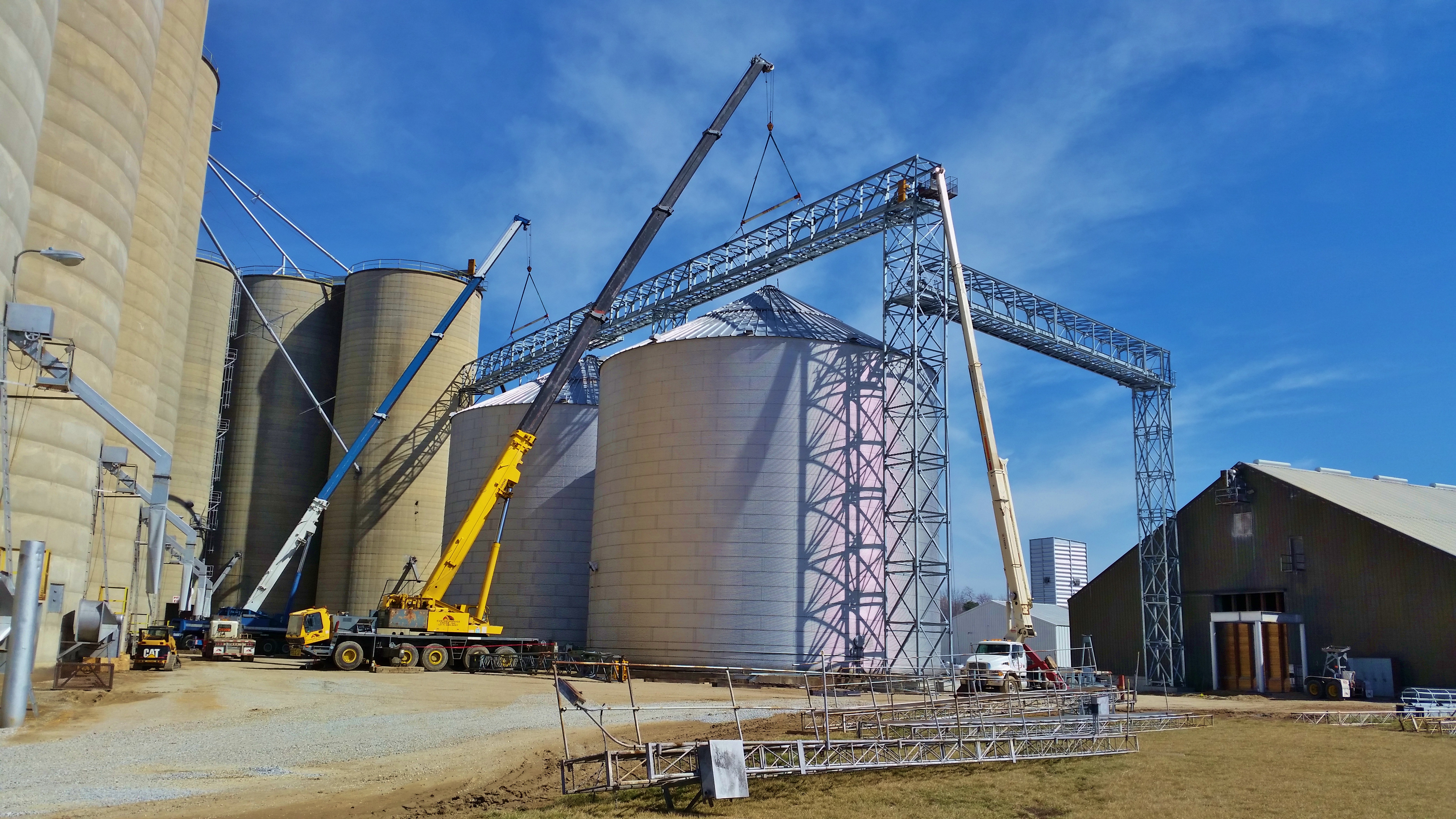 Two 175 ton hydraulic cranes lifting a bridge truss at grain bins